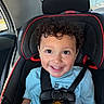 toddler, child, car_seat, seatbelt, curly_hair, smiling, blue_shirt, car_interior, window, happy, cute, safety, portrait, young_child, baby, seat, child_safety, vehicle, daylight, face