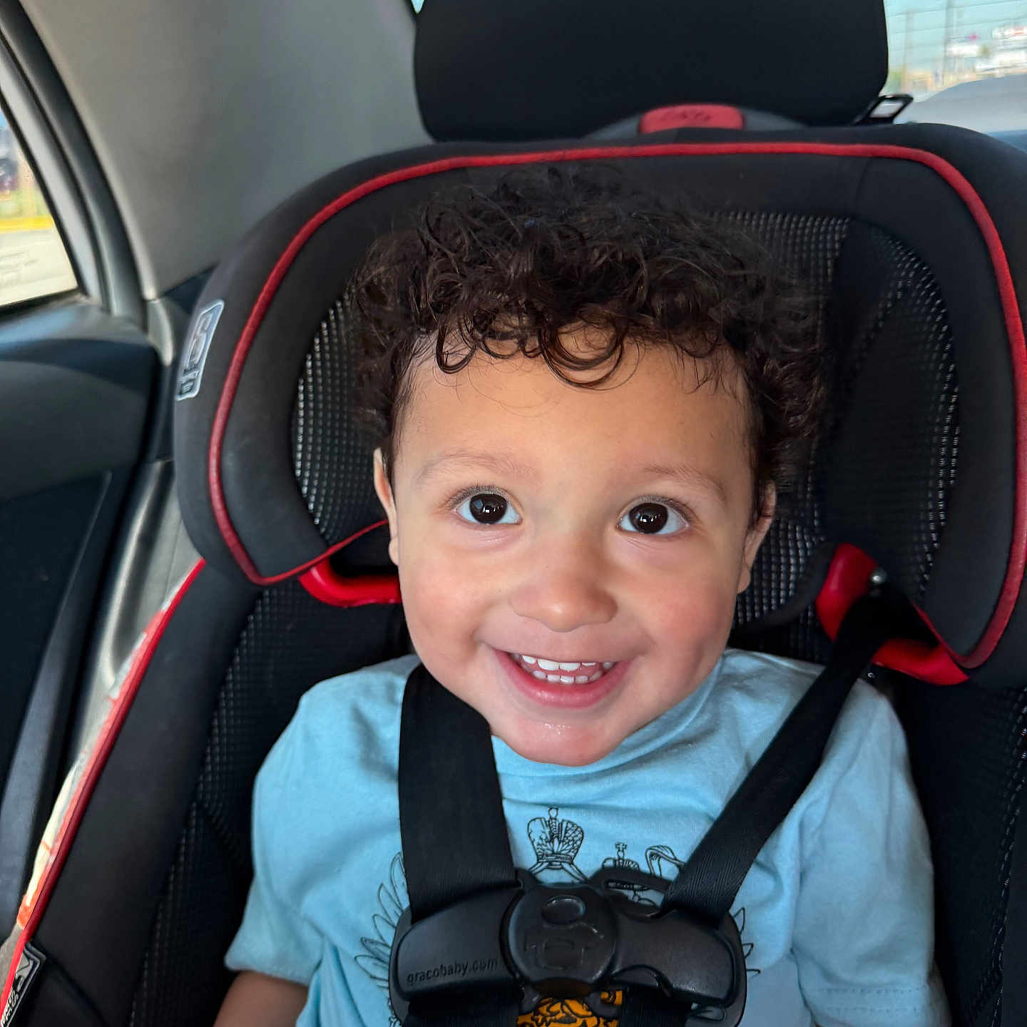 Anthony joined the competition — help win amazing prizes! toddler, child, car_seat, seatbelt, curly_hair, smiling, blue_shirt, car_interior, window, happy, cute, safety, portrait, young_child, baby, seat, child_safety, vehicle, daylight, face