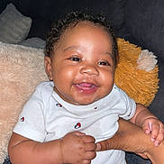 Millionna joined the competition — help win amazing prizes! baby, smiling, curly_hair, onesie, diaper, couch, hand, infant, happy, indoor, person, cute, child, plush_pillow, skin, furniture, seated, young_child, expression, comfort