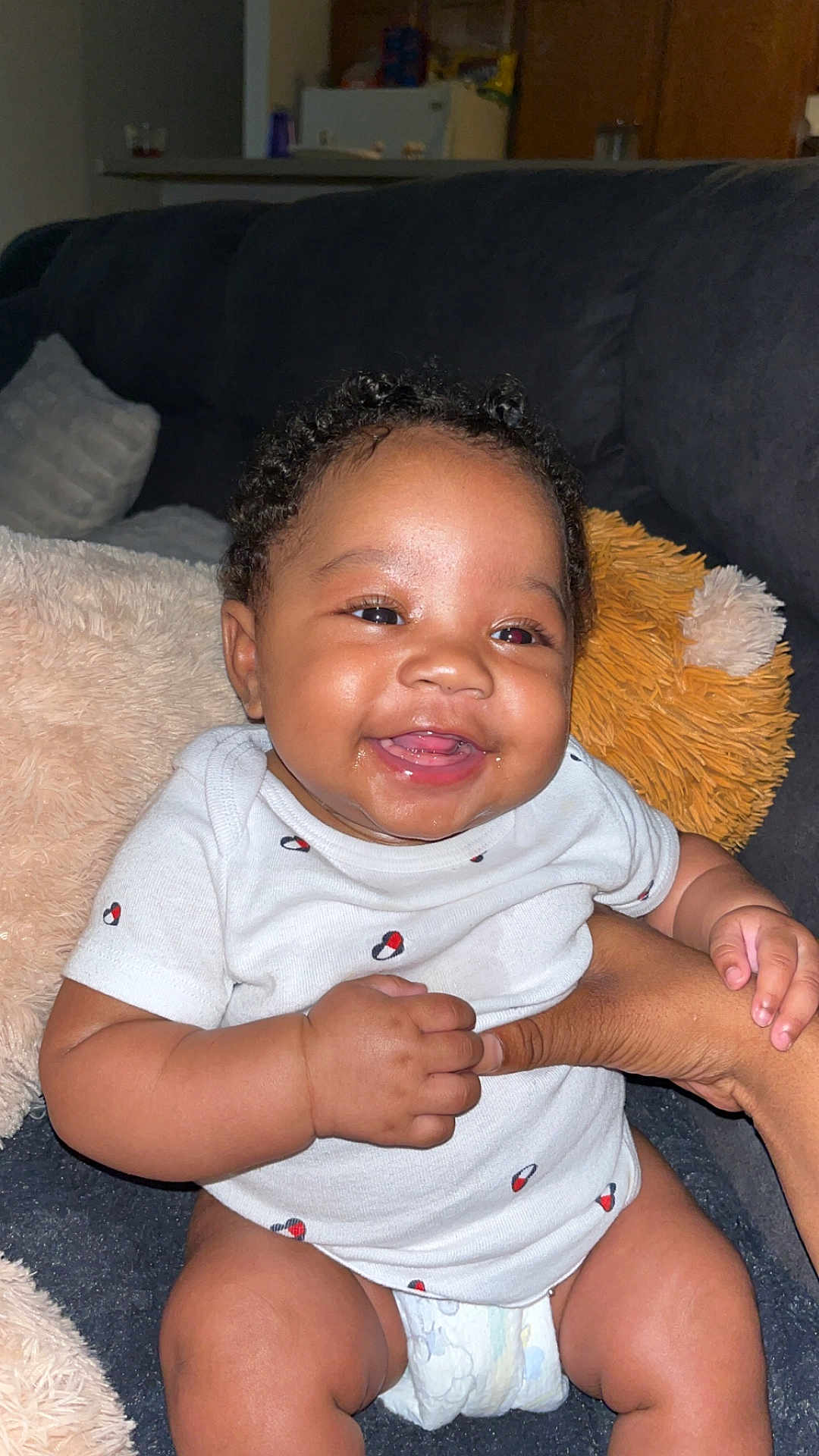 Millionna joined the competition — help win amazing prizes! baby, smiling, curly_hair, onesie, diaper, couch, hand, infant, happy, indoor, person, cute, child, plush_pillow, skin, furniture, seated, young_child, expression, comfort