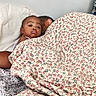 child, baby, blanket, floral_pattern, bed, pillow, adult, sleeping, resting, indoor, person, cozy, comfort, family, portrait, face, head, relaxation, casual, home