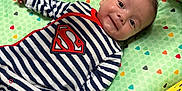 Rafael participe au concours pour gagner de l'argent avec cette photo : baby, infant, striped_clothing, superman_logo, play_mat, animal_prints, smile, lying_down, cute, child, indoors, colorful, soft_toys, happy, face, person, young_child, striped_onesie, cushion, play_area