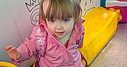 Amelia joined the competition — help win amazing prizes! amusement, backpack, blue_eyes, blue_ride, child, clothing, colorful, curious_expression, footwear, ice_cream_drawings, indoor, kiddie_ride, person, pink_jacket, plastic, playful, portrait, toddler, toy, yellow_seat