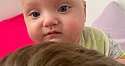 Reily is registered to the contest to win money with this photo: baby, blanket, blue_eyes, brown, child, close_up, curious, cute, expression, face, fuzzy, head, indoor, infant, person, purple_pillow, red_background, skin, soft_lighting, young