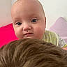 baby, blanket, blue_eyes, brown, child, close_up, curious, cute, expression, face, fuzzy, head, indoor, infant, person, purple_pillow, red_background, skin, soft_lighting, young
