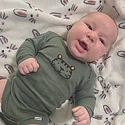 Asher is registered to the contest to win money with this photo: awake, baby, bedtime, blanket, bunny_pattern, chubby_cheeks, clothing, cozy, cute, fabric, face, hands, infant, lying_down, onesie, playful, portrait, smiling, soft_texture, tiger_print