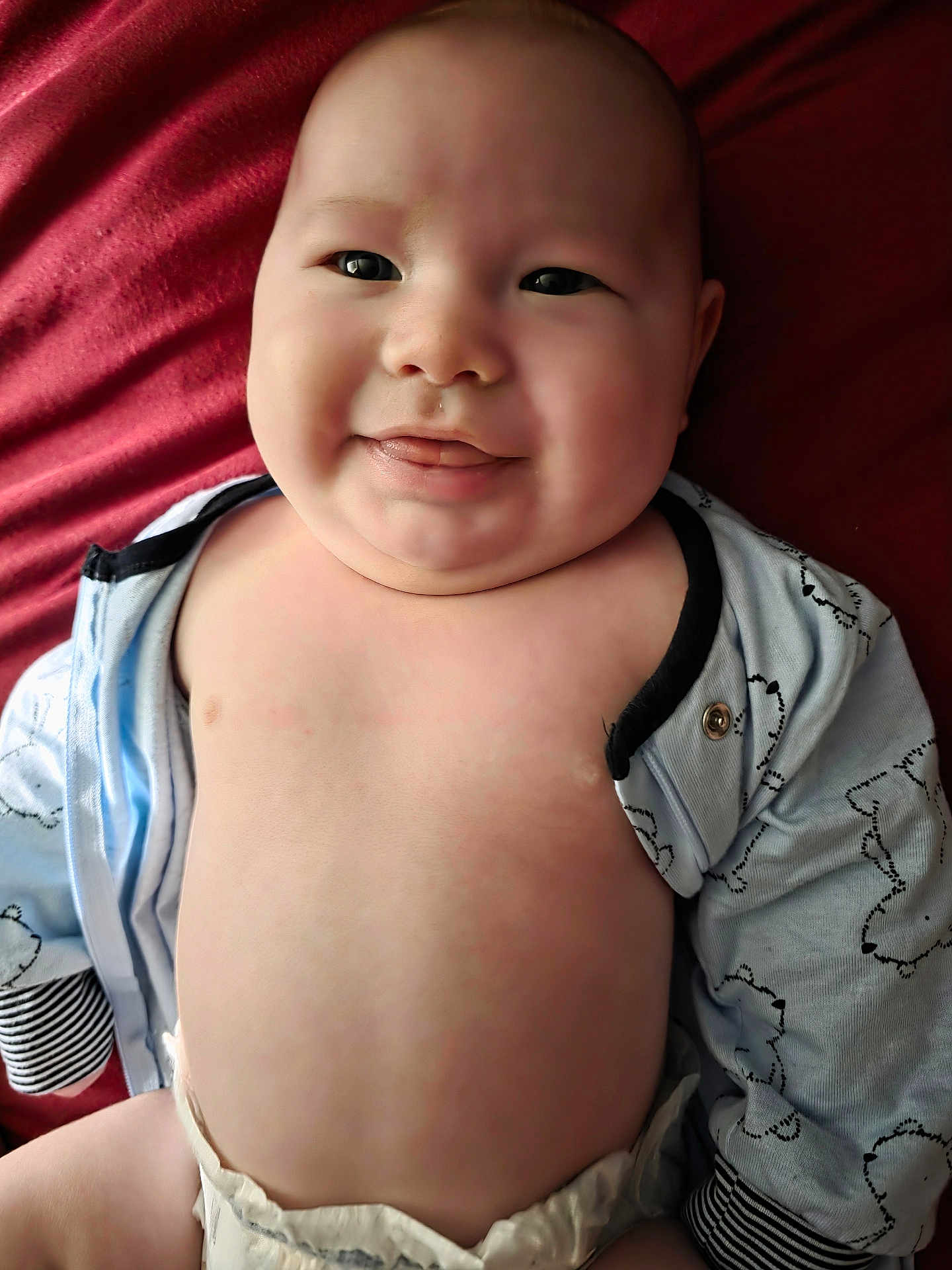Asher is registered to the contest to win money with this photo: baby, infant, smiling, chubby_cheeks, tongue, diaper, onesie, blanket, bedding, portrait, close_up, skin, eyes, face, happy, laying_down, cute, clothing, button, playful