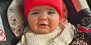 Paisley is registered to the contest to win money with this photo: baby, beanie, car_seat, child, clothing, cute, face, floral_pattern, happy, infant, inside, leopard_print, person, portrait, red_hat, smile, toy, warm_clothing, white_bib, young_child