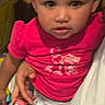 toddler, child, baby, portrait, sitting, pink_shirt, diaper, toy, indoors, lap, person, face, eyes, hair, looking_at_camera, serious_expression, casual_clothing, close_up, portrait_photography, home