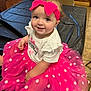 baby, child, birthday, pink, tutu, headband, polka_dot, smile, happy, indoor, table, clothing, person, cute, celebration, sitting, face, dressed_up, toddler, fun