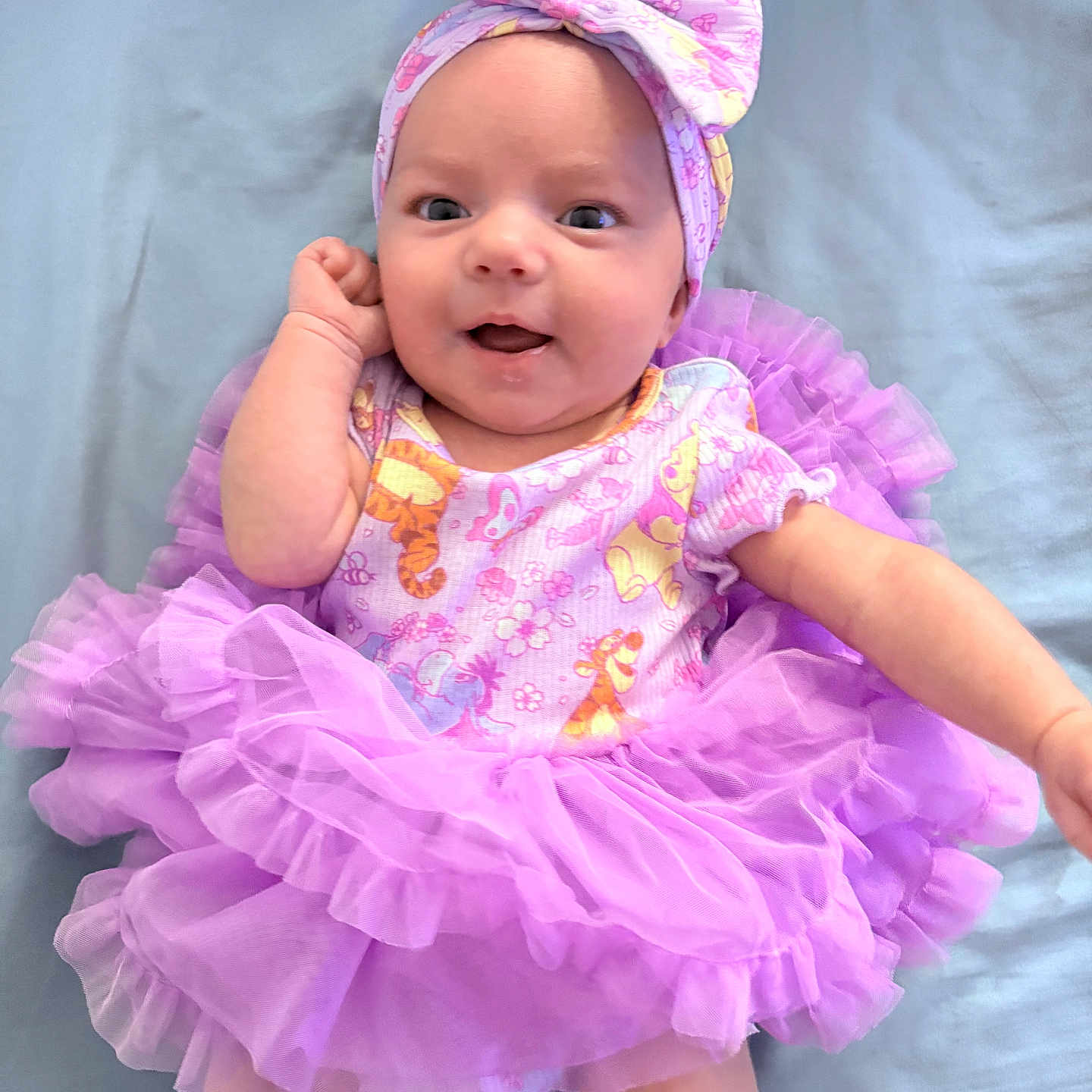 Sienna is registered to the contest to win money with this photo: baby, infant, child, portrait, smiling, happy, face, headband, bow, pink, tutu, dress, floral, costume, lying_down, indoor, backdrop, ballet, fashion, photography