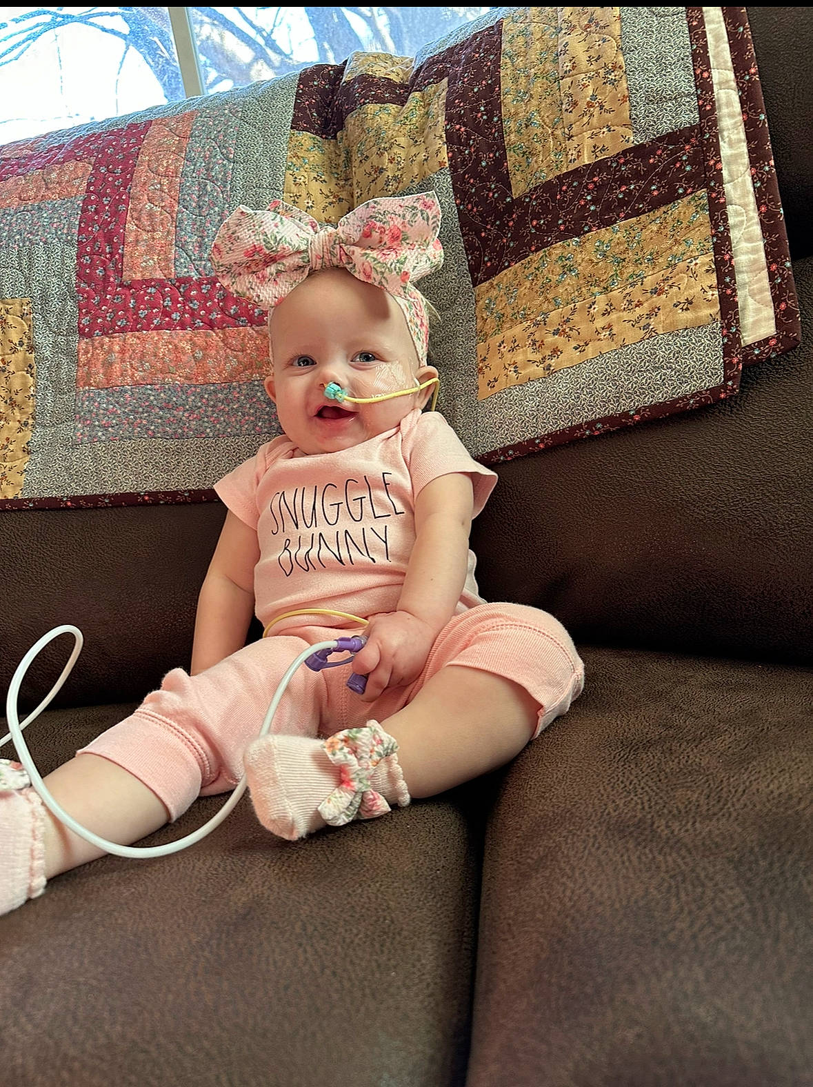 Arabella joined the competition — help win amazing prizes! baby, baby_toddler_clothing, child, comfort, couch, fashion_accessory, flooring, foot, human_leg, linens, living_room, pattern, peach, person, room, sitting, sock, thigh, throw_pillow, toddler