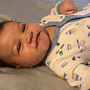 George is registered to the contest to win money with this photo: baby, babywear, bed, child, clothing, cute, expression, face, home, indoors, infant, lying_down, mischievous, onesie, person, portrait, resting, sleepwear, smiling, young