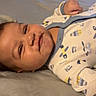 baby, babywear, bed, child, clothing, cute, expression, face, home, indoors, infant, lying_down, mischievous, onesie, person, portrait, resting, sleepwear, smiling, young