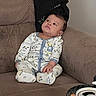 George is registered to the contest to win money with this photo: baby, brown, can, casual, child, clothing, couch, curious, face, furniture, home, indoor, jacket, pajamas, person, relaxing, sitting, snacks, sofa, table