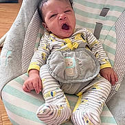 George is registered to the contest to win money with this photo: baby, yawning, pajamas, striped_clothing, baby_rocker, cushion, plush_toy, infant, child, comfortable, indoors, wooden_floor, baby_seat, sleepy, cute, small_hands, small_feet, soft_fabric, pastel_colors, relaxed