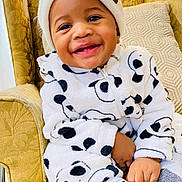 Praise joined the competition — help win amazing prizes! toddler, child, smiling, hat, onesie, panda_pattern, socks, armchair, yellow_curtain, indoor, cozy, happy, portrait, baby, furniture, warm_light, cute, seated, casual_clothing, home