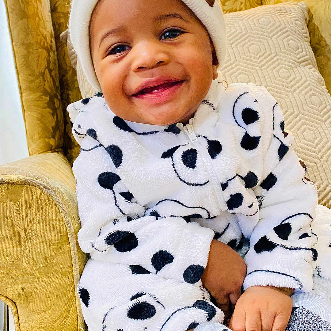 Praise joined the competition — help win amazing prizes! armchair, baby, casual_clothing, child, cozy, cute, furniture, happy, hat, home, indoor, onesie, panda_pattern, portrait, seated, smiling, socks, toddler, warm_light, yellow_curtain