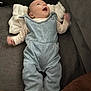 baby, denim_overalls, smiling, happy, infant, couch, blanket, white_socks, indoor, soft_texture, clothing, child, person, portrait, looking_up, cute, cozy, relaxed, home, comfort