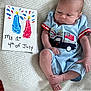 4th_of_july, baby, blanket, blue, blue_outfit, celebration, child, cute, flag, footprint_art, handmade_sign, holiday, indoors, infant, lying_down, newborn, patriotic, portrait, red, white