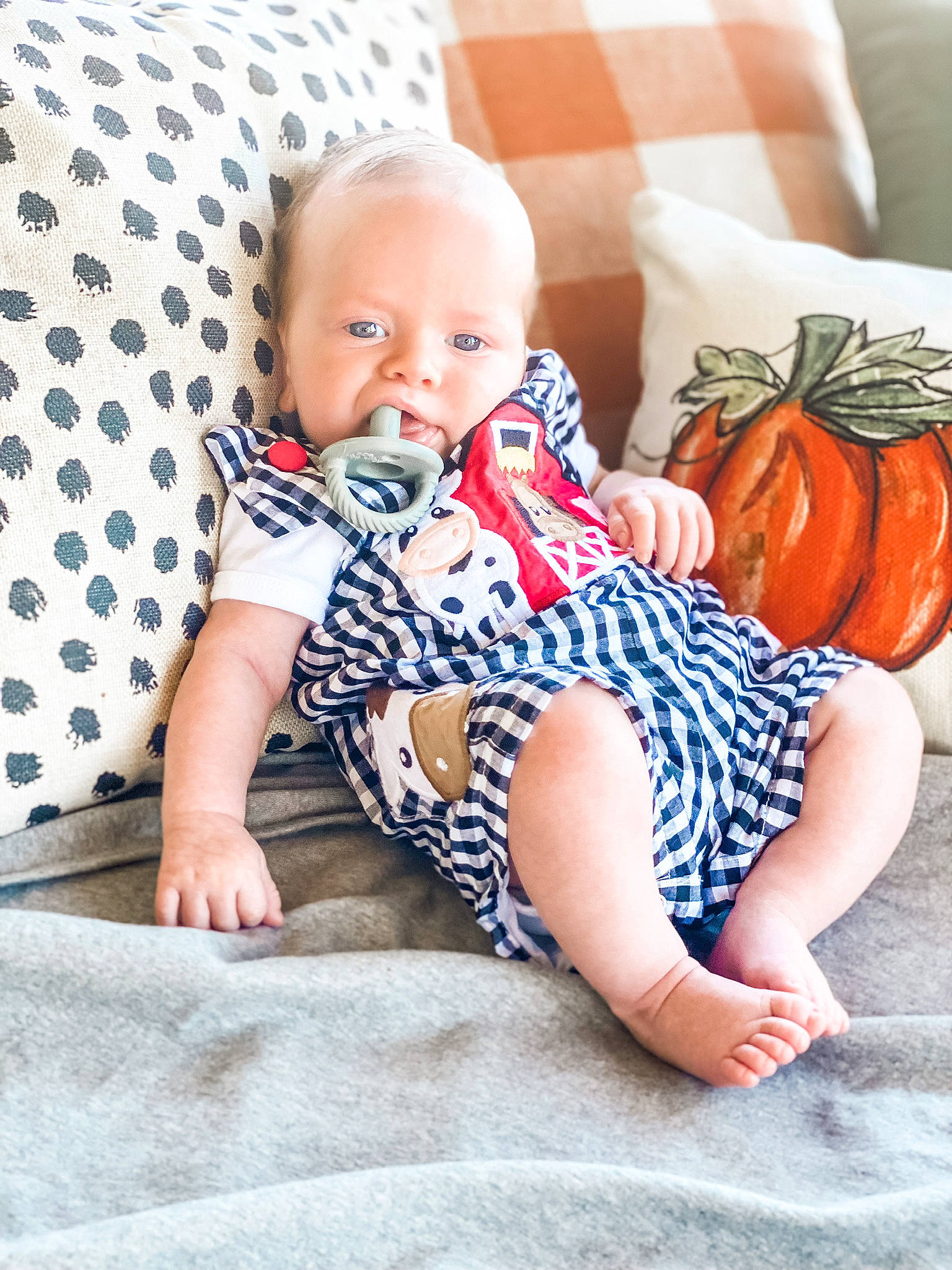 Bodie is registered to the contest to win money with this photo: azure, baby, baby_toddler_clothing, beauty, child, comfort, facial_expression, happy, human_leg, knee, linens, pattern, person, product, pumpkin, sitting, sleeve, t_shirt, thigh, toddler