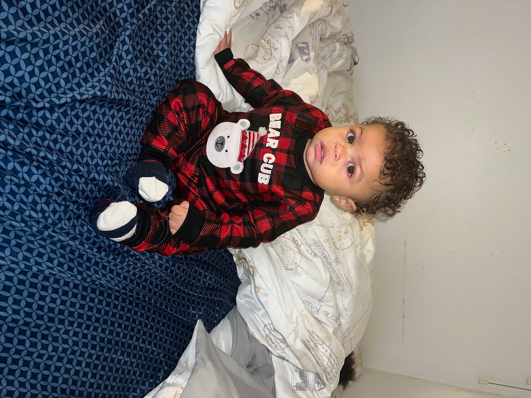 Noah is registered to the contest to win money with this photo: baby, baby_products, baby_toddler_clothing, carmine, child, christmas, comfort, fashion_design, leg, linens, pattern, person, plaid, room, sitting, sleeve, sock, t_shirt, tartan, toddler