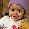 toddler, child, smiling, purple_beanie, sweater, cat_ears, pink_bow, face, portrait, indoors, cute, happy, young_child, person, headwear, clothing, warm_colors, closeup, eyes, cheerful