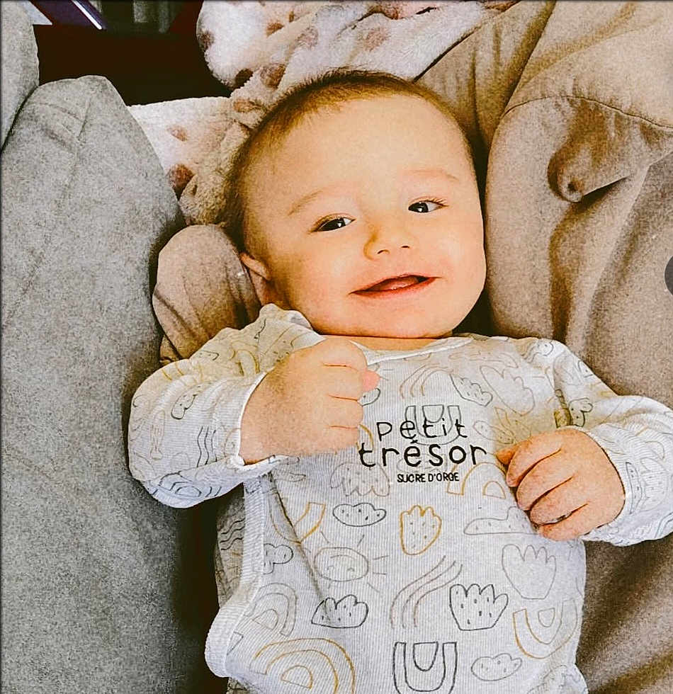 élyas a rejoint le concours — aidez-le/la à gagner de superbes lots ! baby, smiling, infant, onesie, couch, blanket, clothing, face, hand, person, indoor, cute, happy, soft, cozy, furniture, child, portrait, relaxed, young