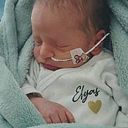 élyas participe au concours pour gagner de l'argent avec cette photo : newborn, baby, infant, blanket, sleeping, medical_tube, teddy_bear_sticker, onesie, name_printed, heart_symbol, soft_texture, wrapped, peaceful, cute, child, portrait, indoors, closeup, face, hand