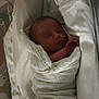 newborn, baby, infant, blanket, hospital, crib, medical_tube, sleeping, wrapped, bed, healthcare, patient, quiet, resting, small, child, person, indoors, soft_lighting, care