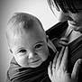 baby, child, smiling, black_and_white, portrait, close_up, face, person, adult, hand, ring, hair, hug, love, bond, babywearing, fabric, skin, parent, affection