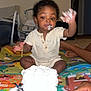 baby, child, cake, frosting, messy, play_mat, indoor, sitting, hand, face, foot, clothing, celebration, party, food, smile, curly_hair, person, toy, home