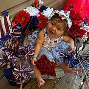 Avaiya is registered to the contest to win money with this photo: baby, blue, blue_tutu, celebration, child, cute, decoration, festive, flowers, happy, headband, outdoor, patriotic, person, red, red_star, sitting, smiling, white, wooden_floor