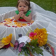 Avaiya is registered to the contest to win money with this photo: baby, child, milk_bath, citrus_slices, strawberries, flowers, butterfly, outdoor, grass, white_cloth, red_hair_ties, green_outfit, cute, portrait, sitting, water, fruit, decorations, summer, nature