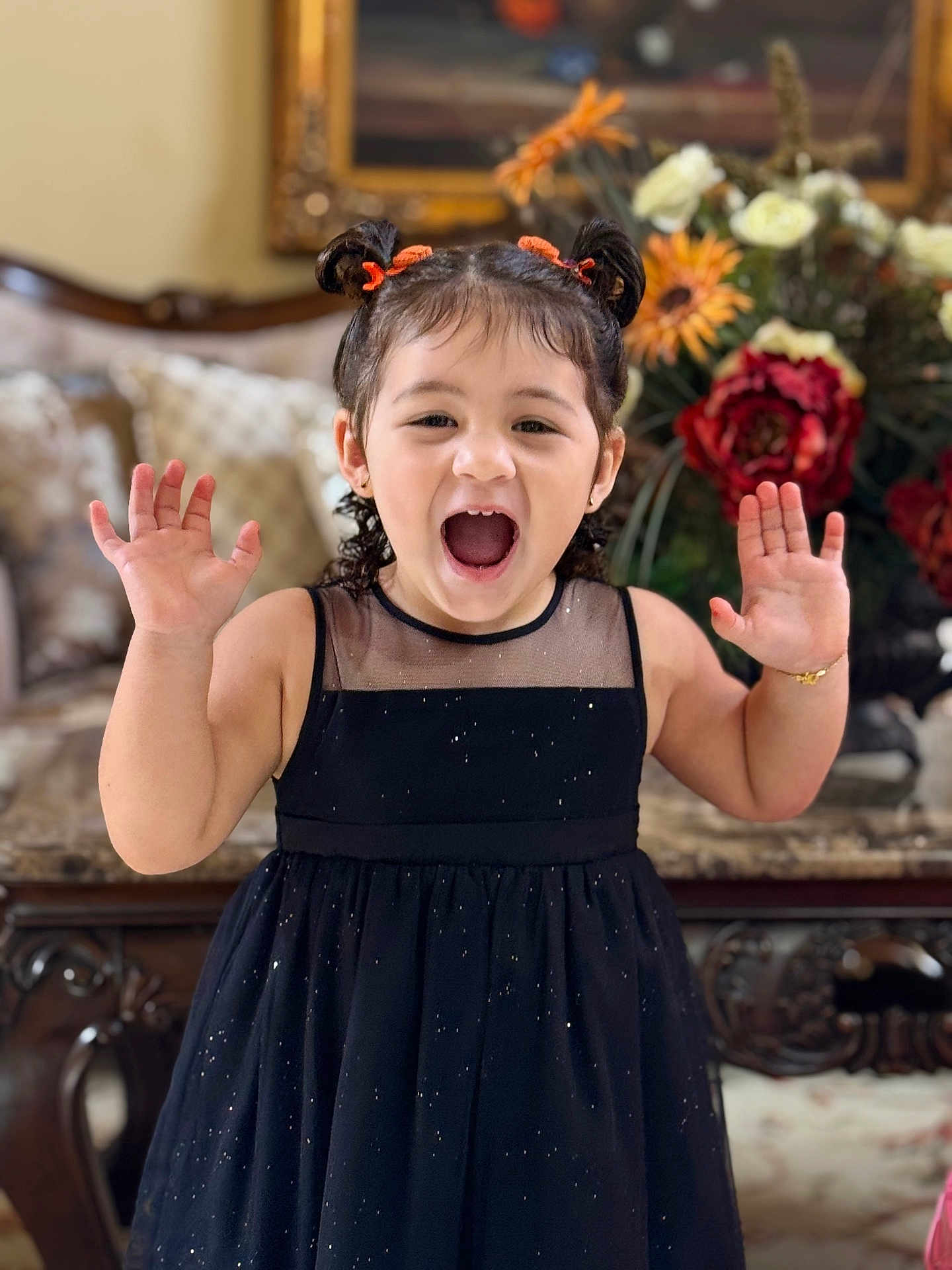 Jamilah joined the competition — help win amazing prizes! child, girl, black_dress, pigtails, orange_hair_ties, smiling, happy, indoor, furniture, flowers, bouquet, portrait, celebration, hands_up, cute, young, person, decor, elegant, joyful