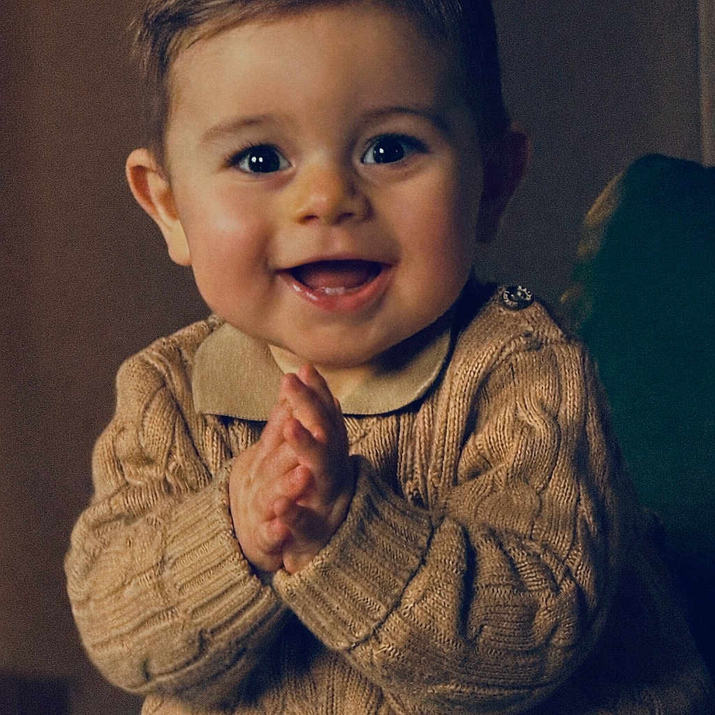 Léao participe au concours pour gagner de l'argent avec cette photo : baby, child, clapping, closeup, cozy, cute, expression, face, hands, happy, indoor, infant, knitted, light, person, portrait, smile, sweater, warm, young