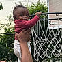 Zyaire joined the competition — help win amazing prizes! baby, child, basketball_hoop, adult_hand, outdoor, trees, net, sky, person, clothing, smile, holding, curious, playing, sport, red_sweater, white_pants, face, grip, fun