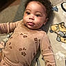 Ava joined the competition — help win amazing prizes! baby, child, infant, curly_hair, pajamas, blanket, paw_prints, lying_down, face, eyes, cute, indoors, soft_lighting, patterned_blanket, person, skin, expression, young, adorable, cozy