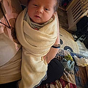 Dawson is registered to the contest to win money with this photo: newborn, baby, infant, child, portrait, face, eyes, hair, swaddled, blanket, cream_blanket, held, adult_hands, bed, bedding, plaid, pillow, indoor, cozy, home