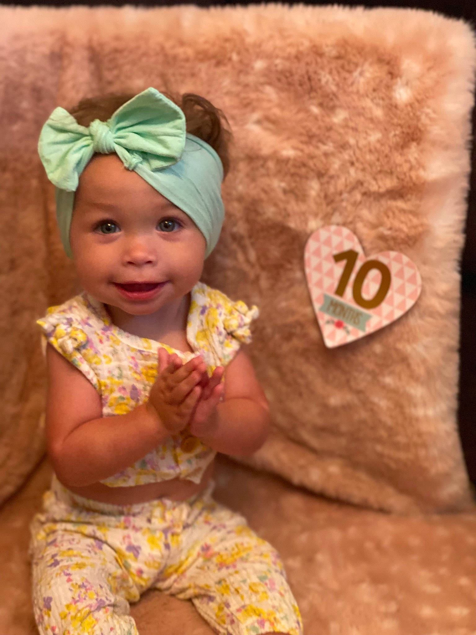 Della is registered to the contest to win money with this photo: baby, baby_toddler_clothing, beanie, cap, child, dress, face, fashion_accessory, fun, happy, headband, headpiece, headwear, human_body, joy, linens, orange, peach, person, sand