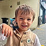 Malone participe au concours pour gagner de l'argent avec cette photo : child, toddler, smiling, face, toy, plush, mickey_mouse, clothing, jacket, urban, sidewalk, street, building, window, trash_can, button, hair, happy, person, portrait