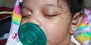 Mulaii is registered to the contest to win money with this photo: baby, sleeping, pacifier, curly_hair, earring, floral_clothing, blanket, closeup, infant, child, peaceful, face, indoors, cute, portrait, resting, soft_lighting, young_child, head, skin