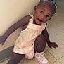 Judea is registered to the contest to win money with this photo: toddler, child, girl, pink_dress, pink_sneakers, hair_accessories, sitting, floor, indoor, tile_floor, wall, playful, happy, curious, person, young_child, casual, cute, smiling, leaning