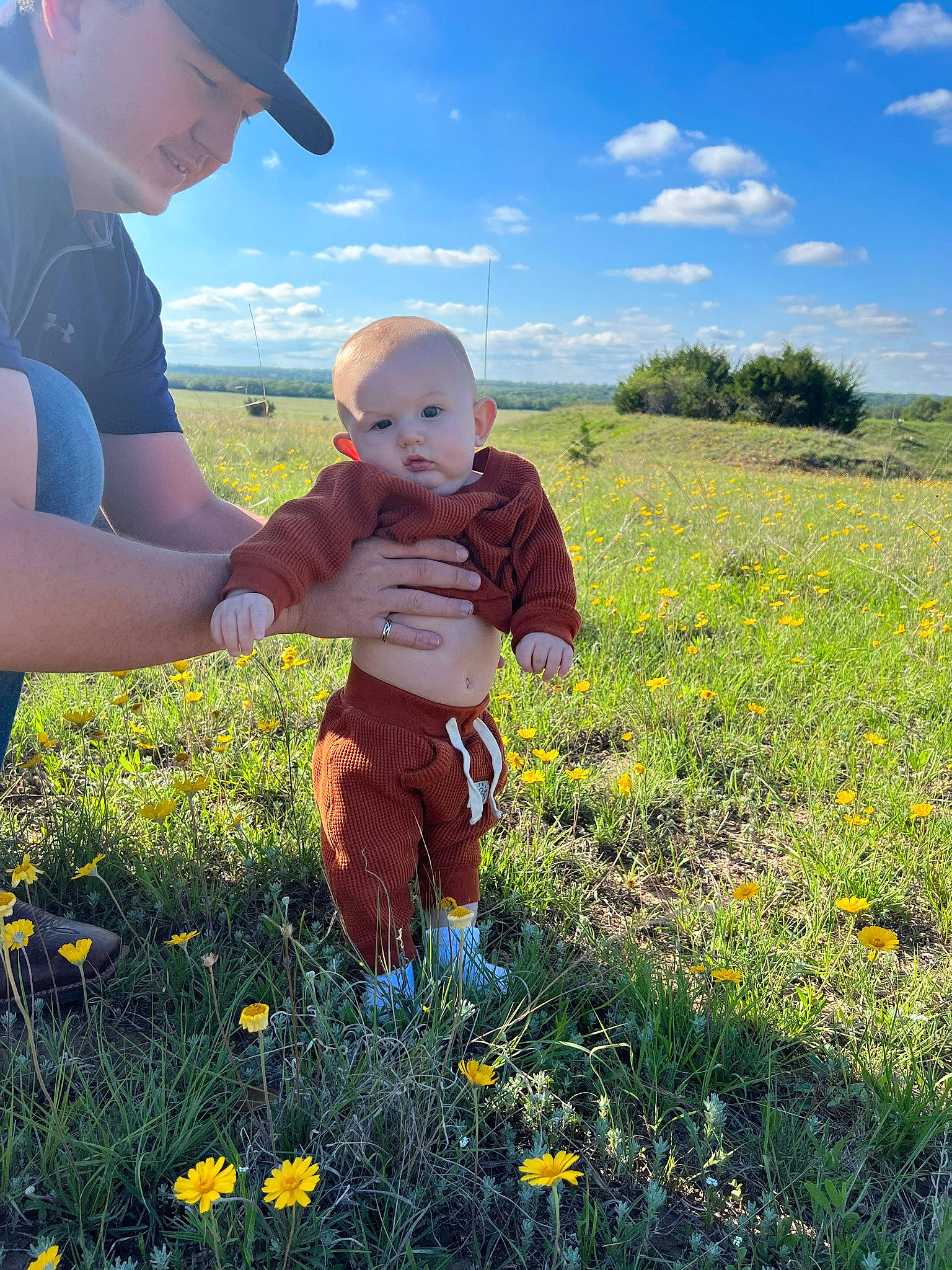 Cohen is registered to the contest to win money with this photo: baby, baby_toddler_clothing, baseball_cap, cloud, flower, gesture, grass, grass_family, grassland, happy, hat, headwear, landscape, meadow, people_in_nature, person, photograph, plant, sky, sun_hat
