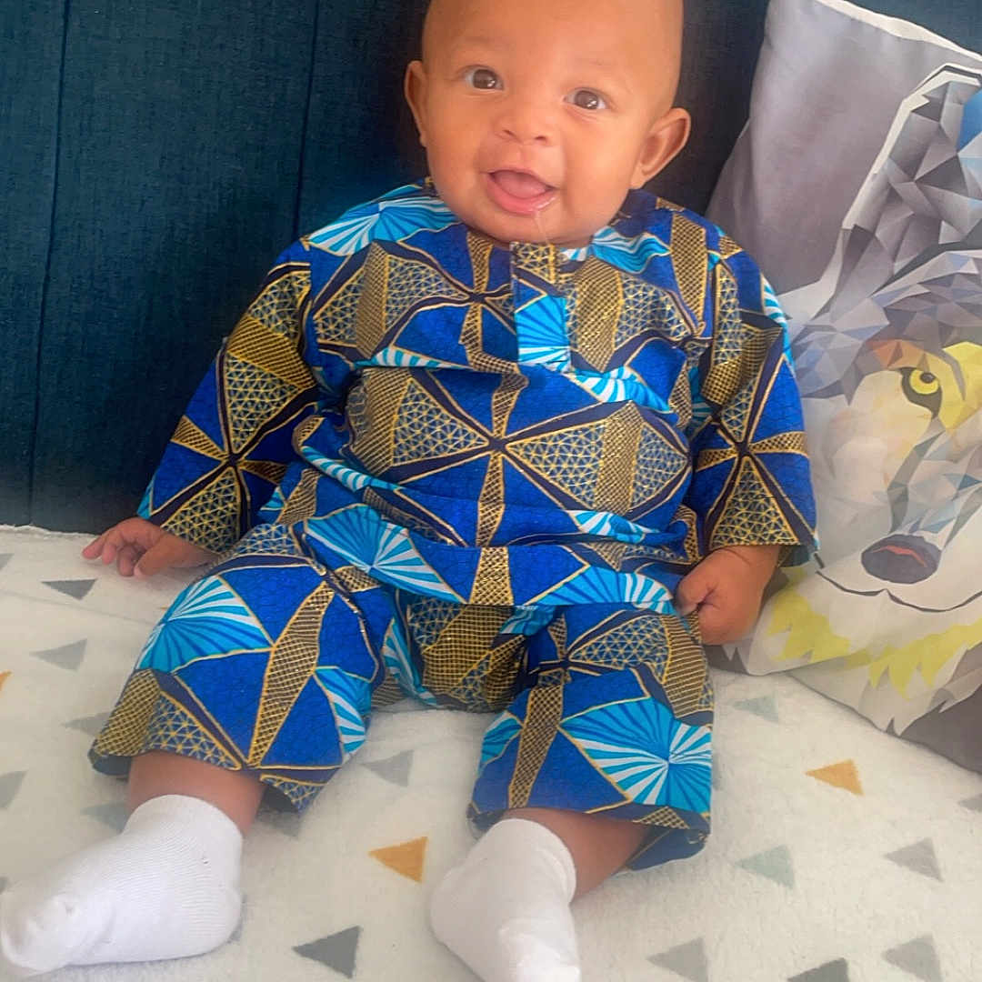 Marah participe au concours pour gagner de l'argent avec cette photo : baby, blanket, clothing, couch, cushion, dress, face, formalwear, furniture, head, homedecor, hosiery, pajamas, pants, person, photography, portrait, quilt, sitting, sock