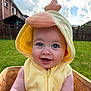 baby, child, costume, yellow, duck, hood, smiling, blue_eyes, flower, basket, outdoor, grass, dandelion, fence, cloudy_sky, happy, cute, portrait, infant, sunlight