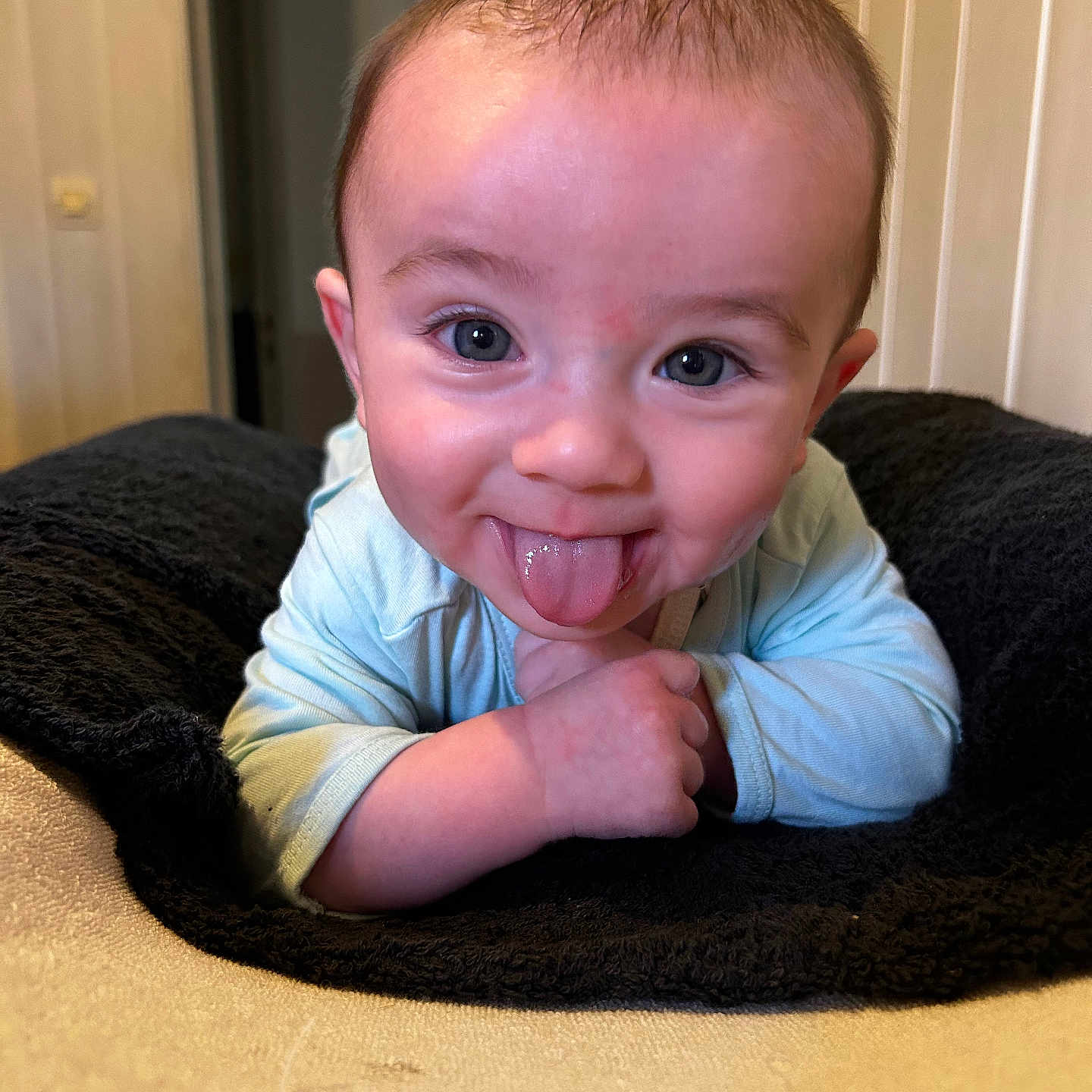 Elyzio participe au concours pour gagner de l'argent avec cette photo : baby, blanket, blue_eyes, child, clothing, cute, expression, face, happy, head, indoor, infant, lying_down, person, playful, portrait, skin, smiling, tongue_out, young_child