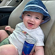 Elyzio a rejoint le concours — aidez-le/la à gagner de superbes lots ! baby, child, smiling, hat, bucket_hat, tshirt, car_seat, energy_drink, red_bull, can, hand, happy, person, indoors, seat, clothing, cute, infant, portrait, leisure