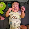 Hector is registered to the contest to win money with this photo: baby, baby_boy, baby_girl, cheerful, child, clothing, cute, dark_hair, happy, indoor, infant, lying_down, onesie, pacifier, person, playful, plush_toy, raising_hands, smiling, soft_surface