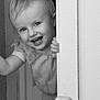 toddler, child, smiling, face, door, peek, black_and_white, portrait, happy, hand, clothing, indoor, cute, young, person, baby, playful, hair, expression, standing